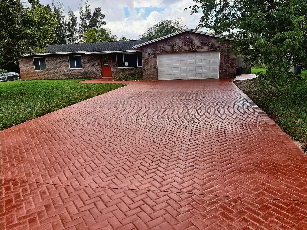 Red stamped concrete driveway in a herringbone brick pattern
