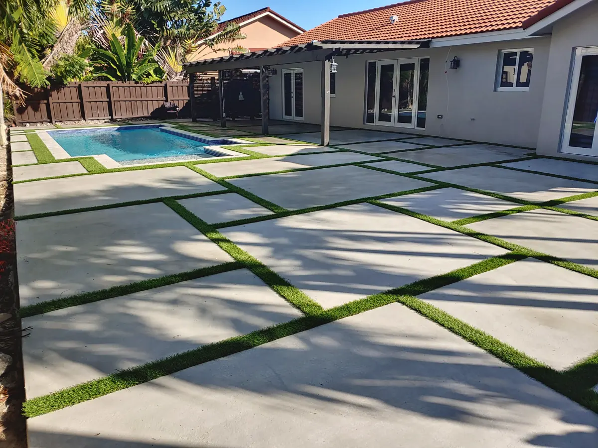 Large backyard concrete slabs with turf joints around a pool and pergola