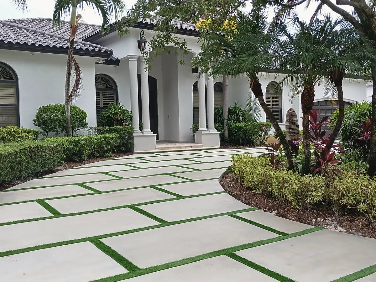 Curved concrete slab driveway with artificial turf joints leading to a home entrance