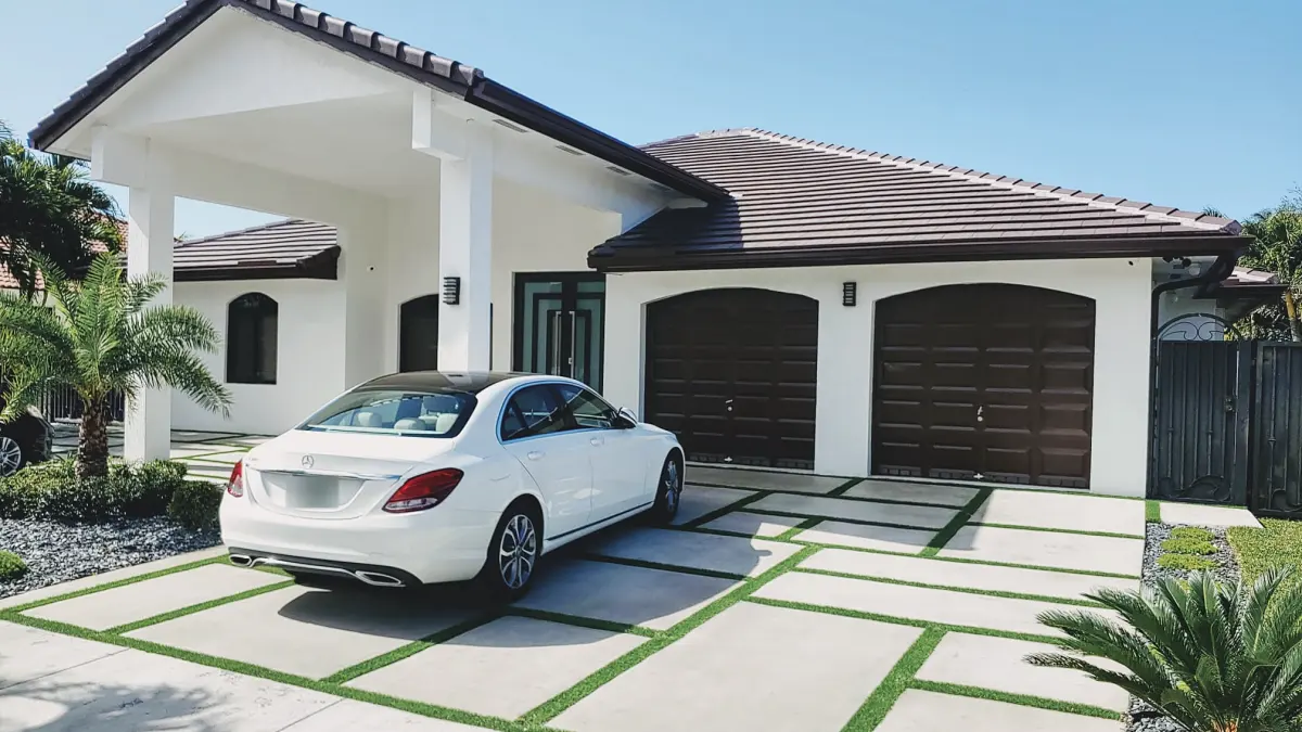 Concrete slab driveway with turf joints at a white single-story home